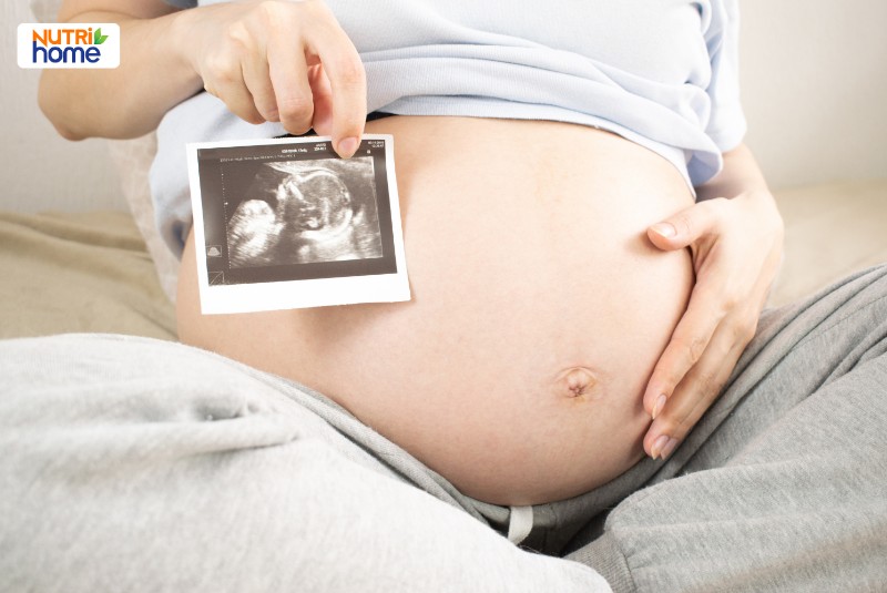 Phụ nữ mang thai cầm ảnh siêu âm thai nhi trên bụng
