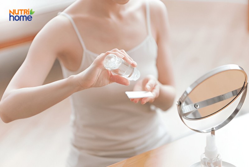 Người phụ nữ đang dùng toner chăm sóc da trước gương