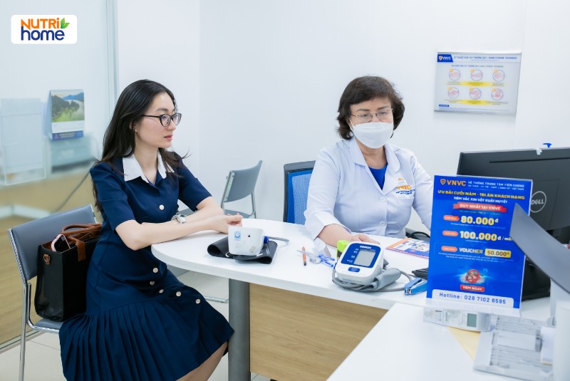 Bệnh nhân nữ được bác sĩ tư vấn trước khi tiêm vắc xin tại phòng khám