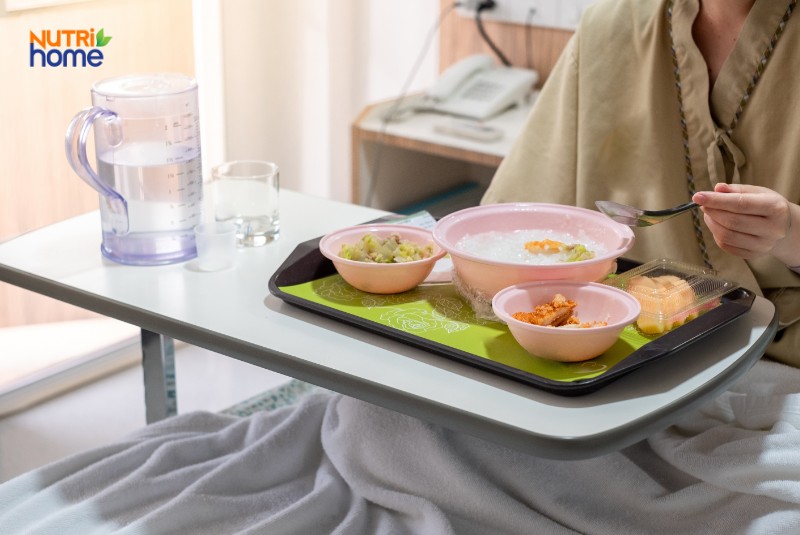 Người bệnh sau mổ sỏi mật đang ăn cháo cùng rau củ và nước lọc tại phòng bệnh