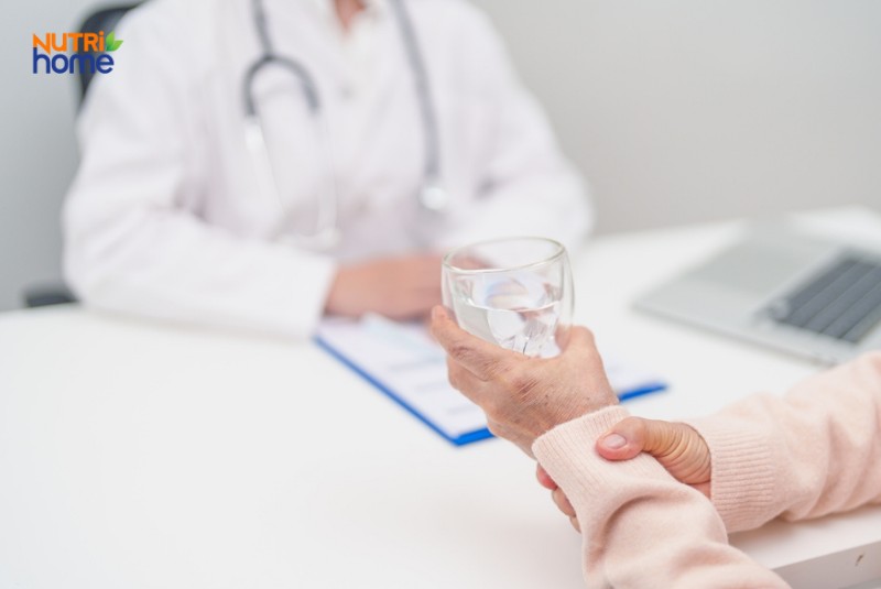 Bệnh nhân cầm ly nước trao đổi với bác sĩ về cách điều trị sỏi mật