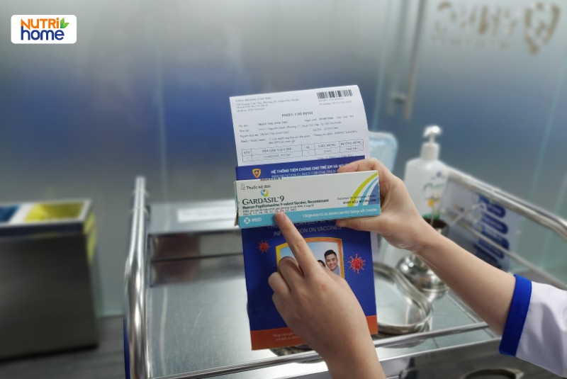 Nhân viên y tế cầm hộp vắc xin Gardasil 9 và phiếu tiêm tại trung tâm tiêm chủng VNVC