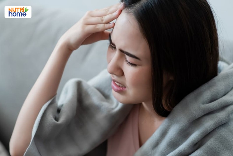 Người phụ nữ mệt mỏi ôm đầu vì đau đầu, biểu hiện của nhiễm virus Nipah