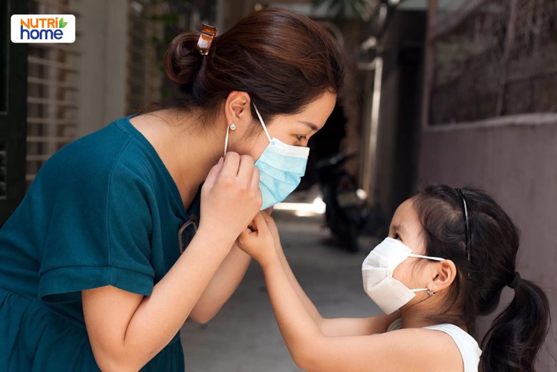 Mẹ giúp con đeo khẩu trang để phòng ngừa lây nhiễm virus Nipah