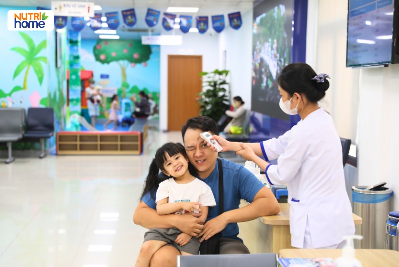 Nhân viên y tế kiểm tra nhiệt độ cho bé gái tại khu vực khám bệnh VNVC