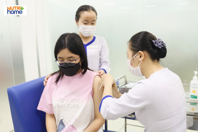 Nữ sinh đeo khẩu trang được tiêm vắc xin phòng HPV bởi nhân viên y tế tại VNVC