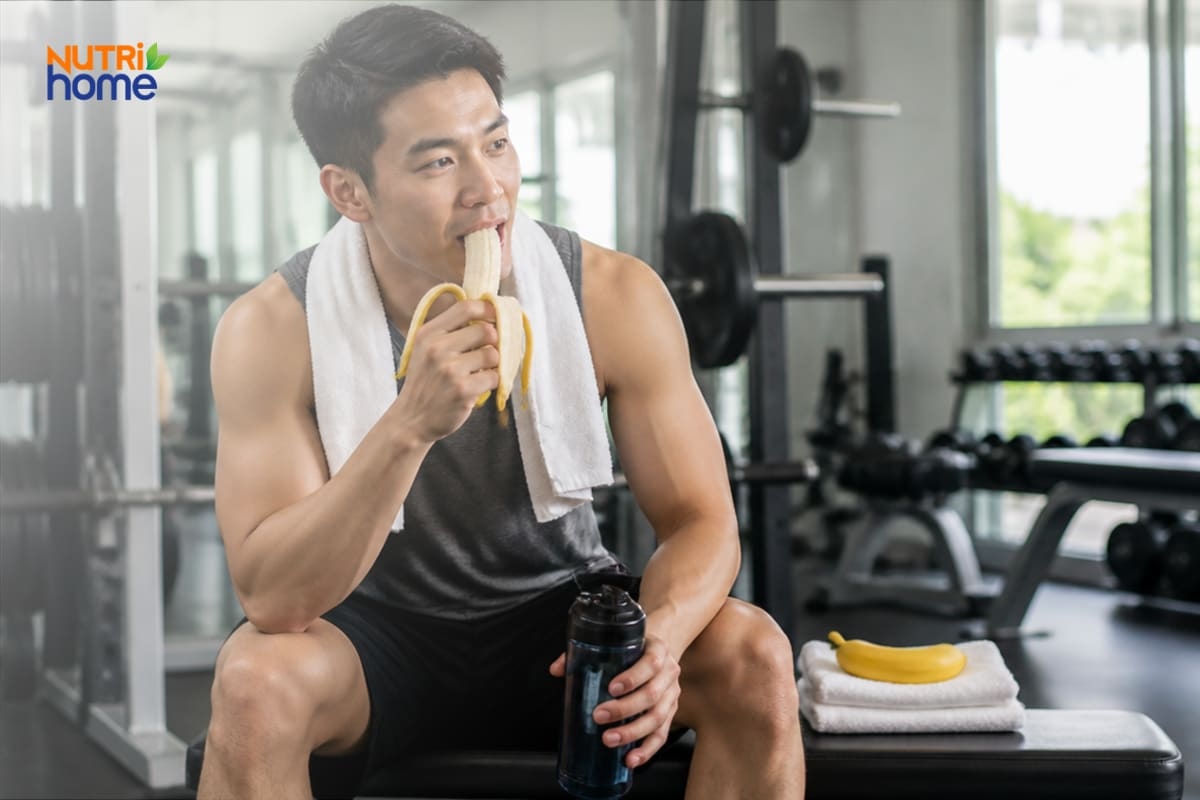 Nam giới ăn chuối và uống nước sau buổi tập gym để phục hồi năng lượng
