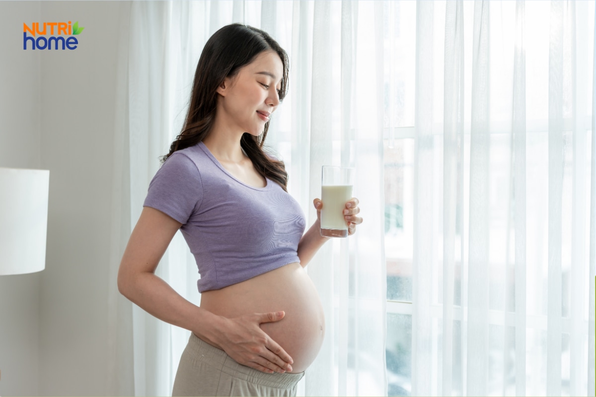 Mẹ bầu cầm ly sữa bên cửa sổ