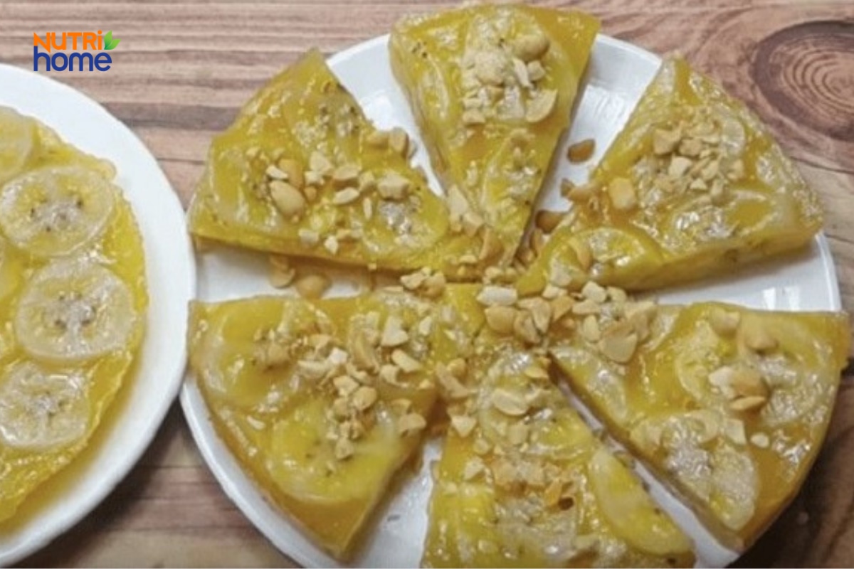Các miếng bánh chuối hấp màu vàng trong, dẻo, rắc đậu phộng trên đĩa.