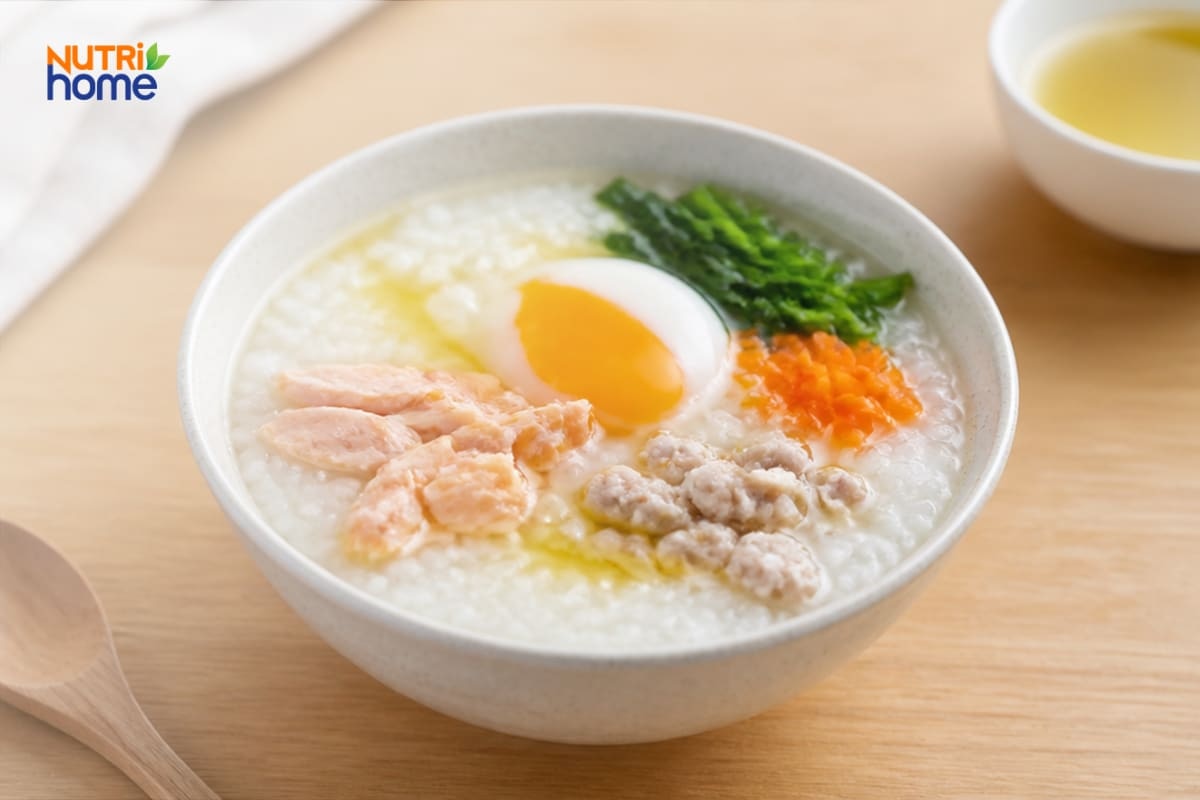 Bát cháo kết hợp thịt, trứng, cà rốt và rau xanh.