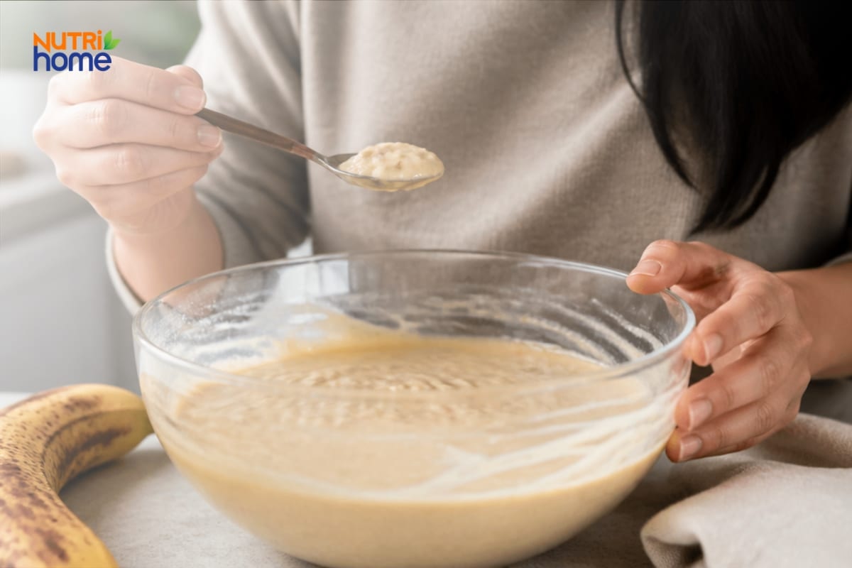 Người làm bánh nếm hỗn hợp bột chuối trong tô trước khi nướng.