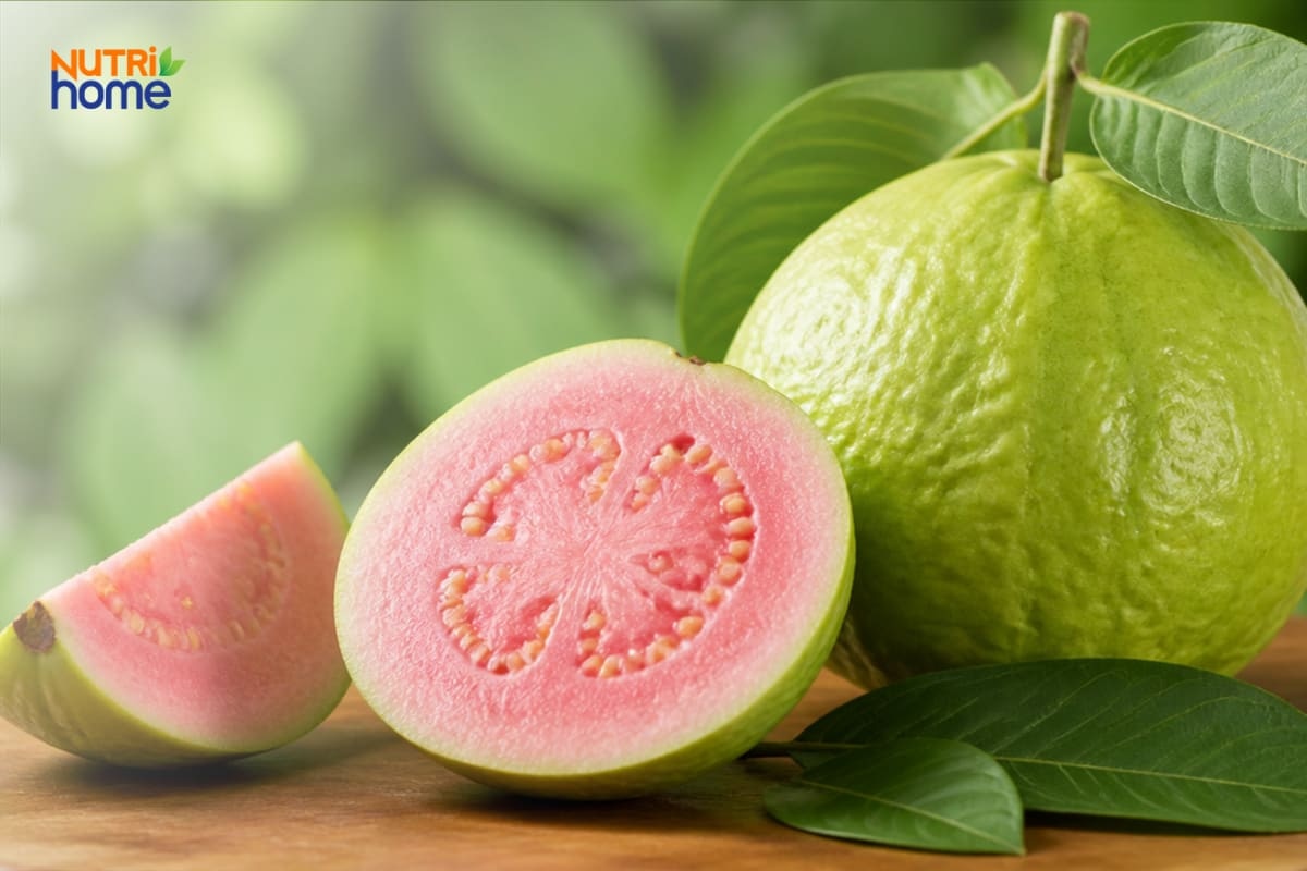 Ổi ruột hồng tươi nguyên quả và bổ đôi trên bàn gỗ.