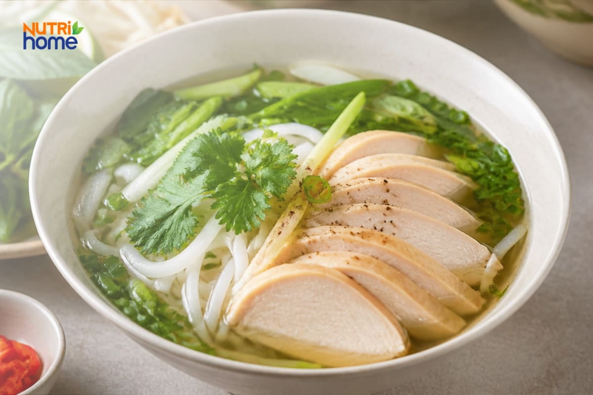 Tô phở gà với thịt nạc, rau xanh và hành ngò.