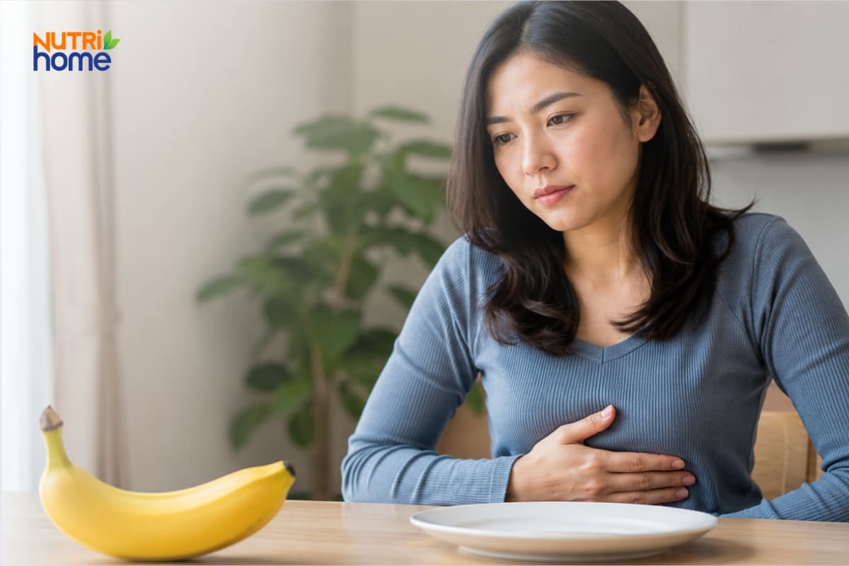 Người phụ nữ ôm bụng bên cạnh quả chuối và chiếc đĩa trống