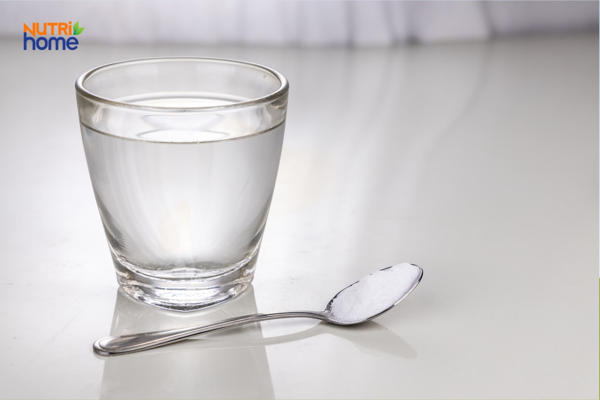 Một ly nước đặt cạnh thìa chứa muối trên mặt bàn.