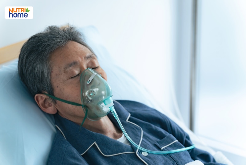 Người cao tuổi nằm điều trị và sử dụng mặt nạ hỗ trợ thở oxy.