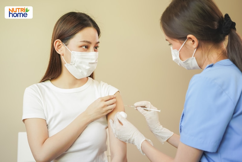 Người phụ nữ được nhân viên y tế tiêm vắc xin vào cánh tay.