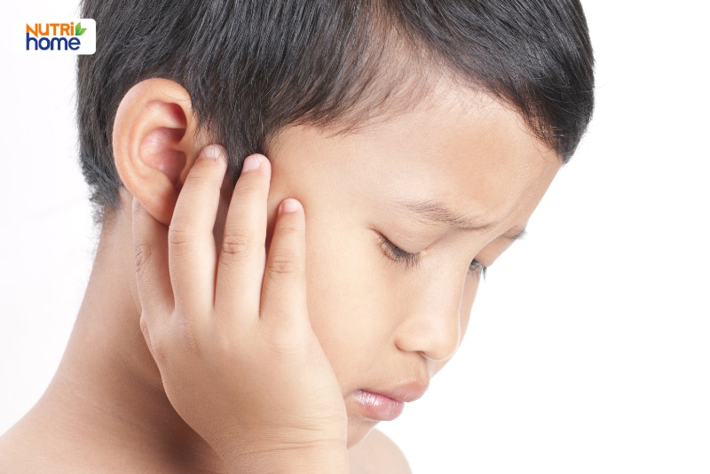 Bé trai đặt tay lên tai với biểu hiện đau và khó chịu.