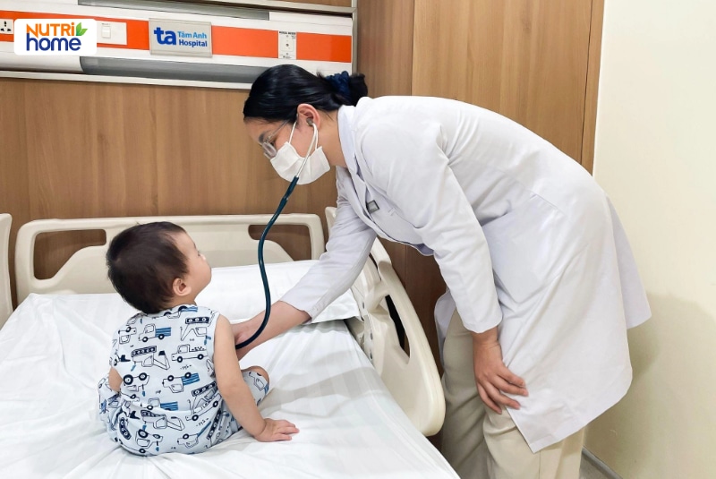 Bác sĩ dùng ống nghe khám cho bé trai ngồi trên giường bệnh