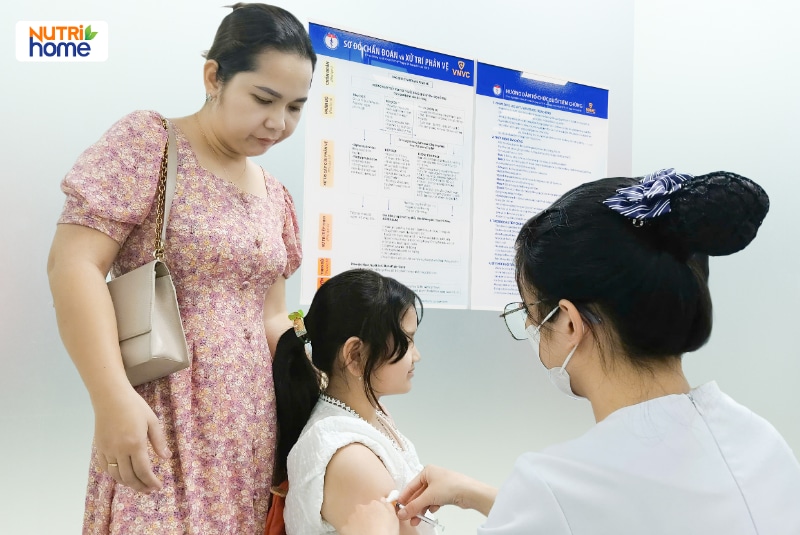 Bé gái được nhân viên y tế tiêm vắc xin tại trung tâm tiêm chủng