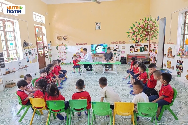 Lớp mầm non sạch sẽ với trẻ ngồi thành vòng tròn nghe cô hướng dẫn
