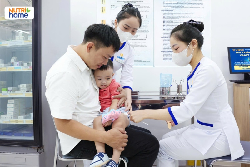 Điều dưỡng tiêm vắc xin cho bé được bố bế tại trung tâm VNVC